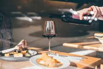 Waiter pouring red wine for customers in restaurant.
