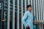 Confident young Asian man with laptop, looking away while standing in financial district. Business, finance and investment. Concept of business mobility.
