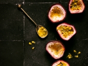 top down view of halved passion fruits  on black backdrop with seeds. copy space
