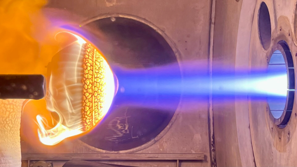 a bright plume of blue fire blasts onto a red-orange domed surface inside a concrete tunnel