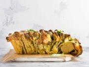 Pull-apart bread with Italian pasta pesto, basil and parmesan cheese in baking form over old light concrete background. Top view. Rustic stile.