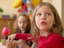 5 years old girl sitting on a table at a party.
