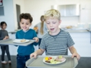 Pupils carrying trays in school canteen