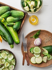 Slicing fresh vegetable crops. Preparing healthy meal with zucchini and cucumber. Ripe zucchini and cucumber on white table background