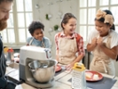 Group of happy children laughing during cooking lesson with cook in the kitchen