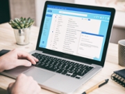 Email message communication. Man working with a computer, client mail list on laptop screen, office desk background.