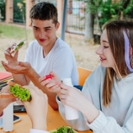 Girls with boy having lunch sitting at table in schoolyard