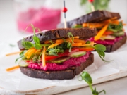 gluten free vegan sandwiches with beet hummus, raw vegetables and sprouts. soft focus