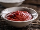 Tomato paste, sauce, ketchup in a white bowl on a wooden table - Close up.