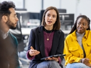 Young woman sharing her ideas with team sitting in circle at office. Business team having meeting at work.