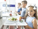 Girl holding food tray standing in school cafeteria