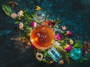 A geometrical composition with cup of herbal tea with flowers, leaves, herbs and small on a marble background
