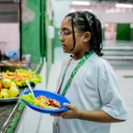 Schoolgirl holding a healthy plate lunch in the cafeteria at school - Including people with autism